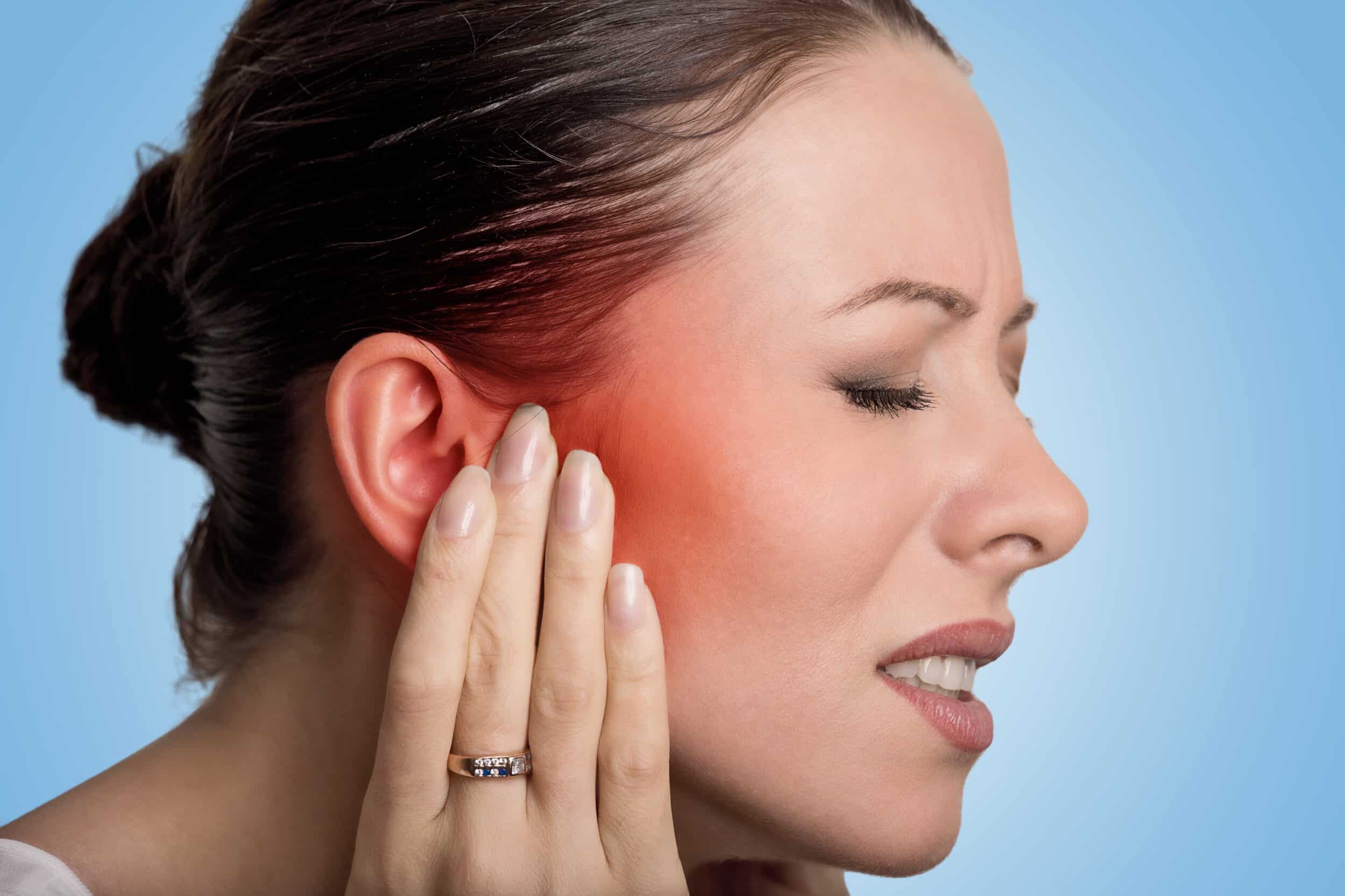 A close-up profile shot of a woman holding her ear because of an ear condition